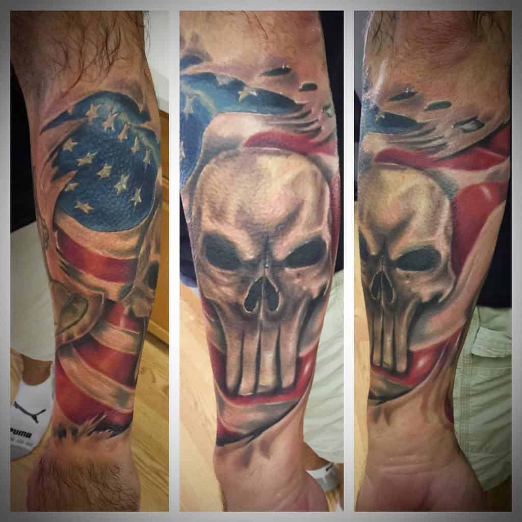 Punisher Skull tattoo wrapped in an American flag design, covering the forearm with rich colors and detailed shading to create a patriotic and intense look