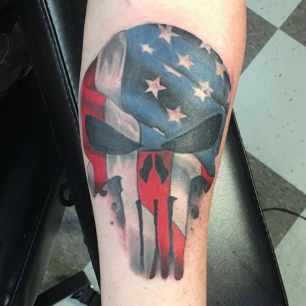 Punisher Skull tattoo on the forearm, featuring an American flag overlay with bold colors and shading for a striking patriotic effect