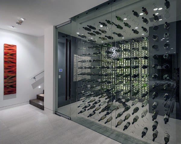 Modern wine cellar with glass walls and rows of wine bottles, featuring a contemporary staircase and abstract artwork