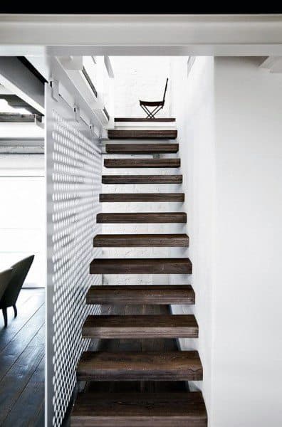Modern wooden staircase with a lattice wall on the left and a cozy chair waiting at the top