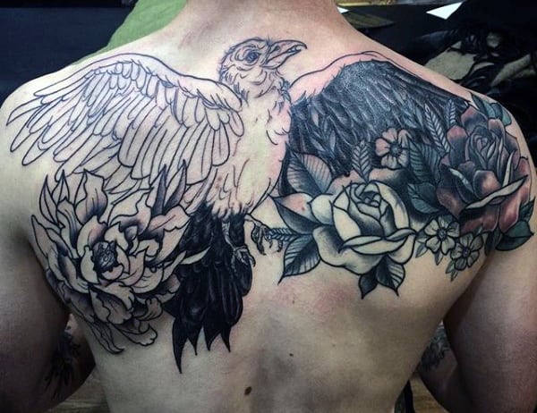 Back tattoo of a detailed bird with outstretched wings surrounded by various flowers