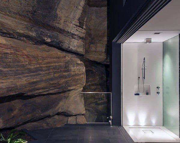 Stunning shower design featuring natural stone wall, modern fixtures, and sleek LED floor lighting for a luxurious, spa-like atmosphere