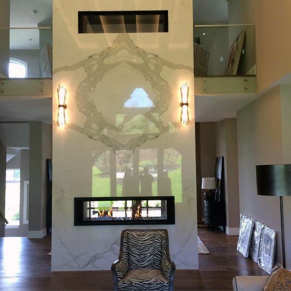 Double-sided gas fireplace with a sleek black frame set in a floor-to-ceiling marble surround.