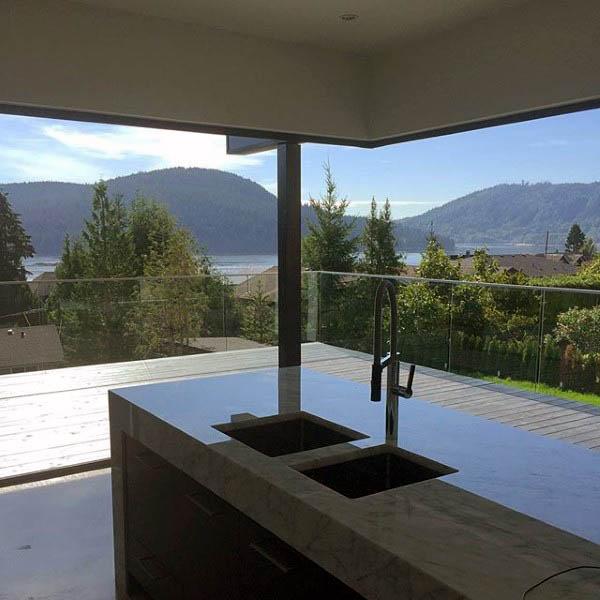 Modern kitchen with marble island, floor-to-ceiling windows, and scenic mountain views.