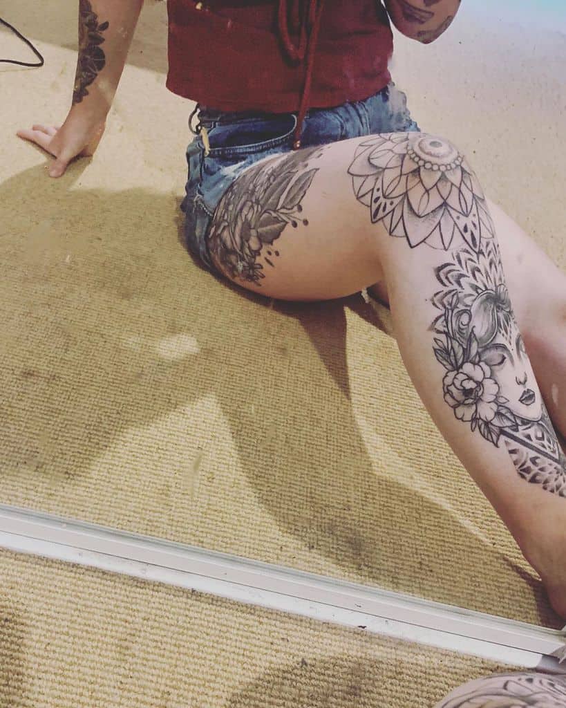 Black and grey tattoo leg sleeve featuring intricate floral designs and a woman’s portrait complemented by a geometric mandala