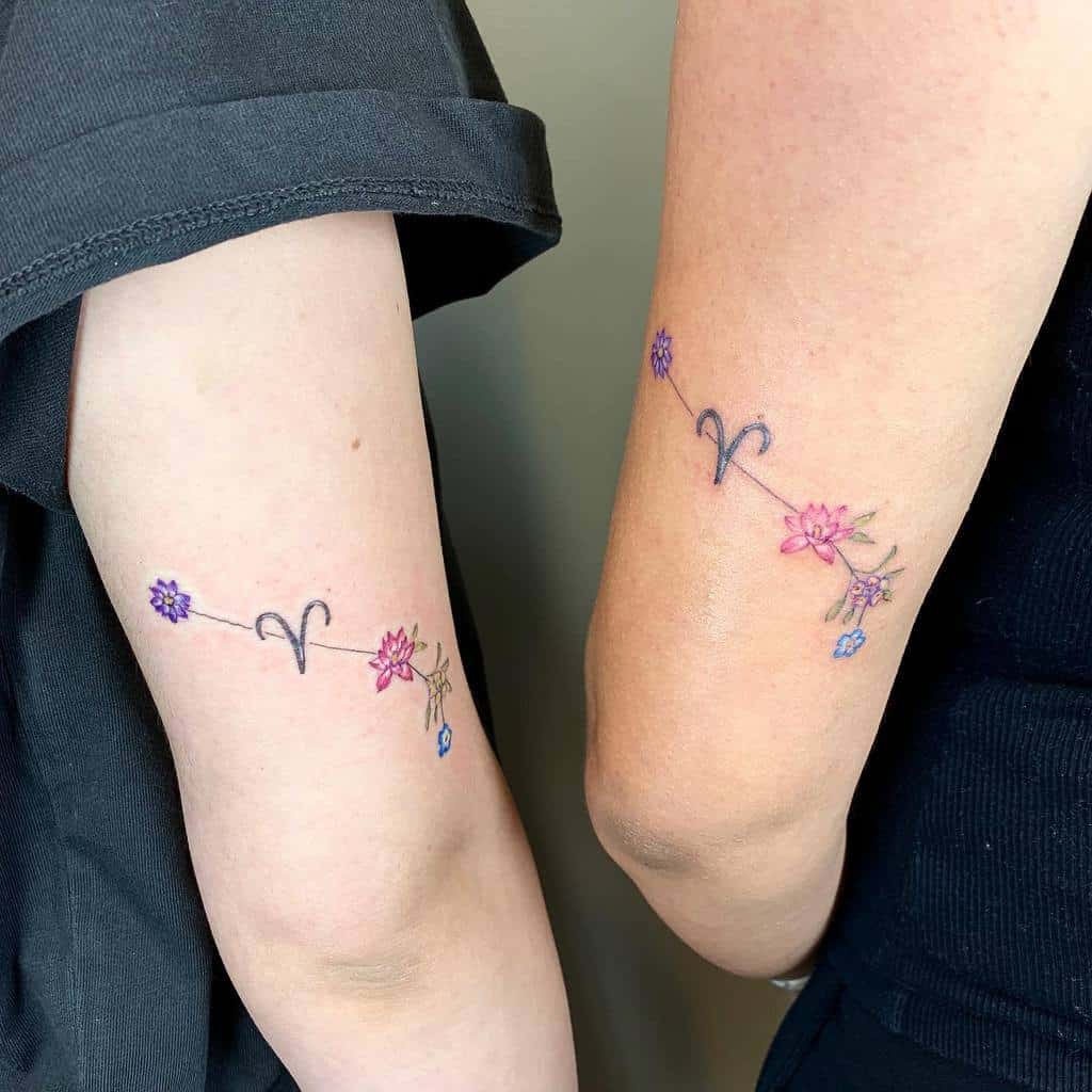 Matching sister tattoos featuring delicate floral designs connected by an Aries zodiac symbol, representing shared bonds