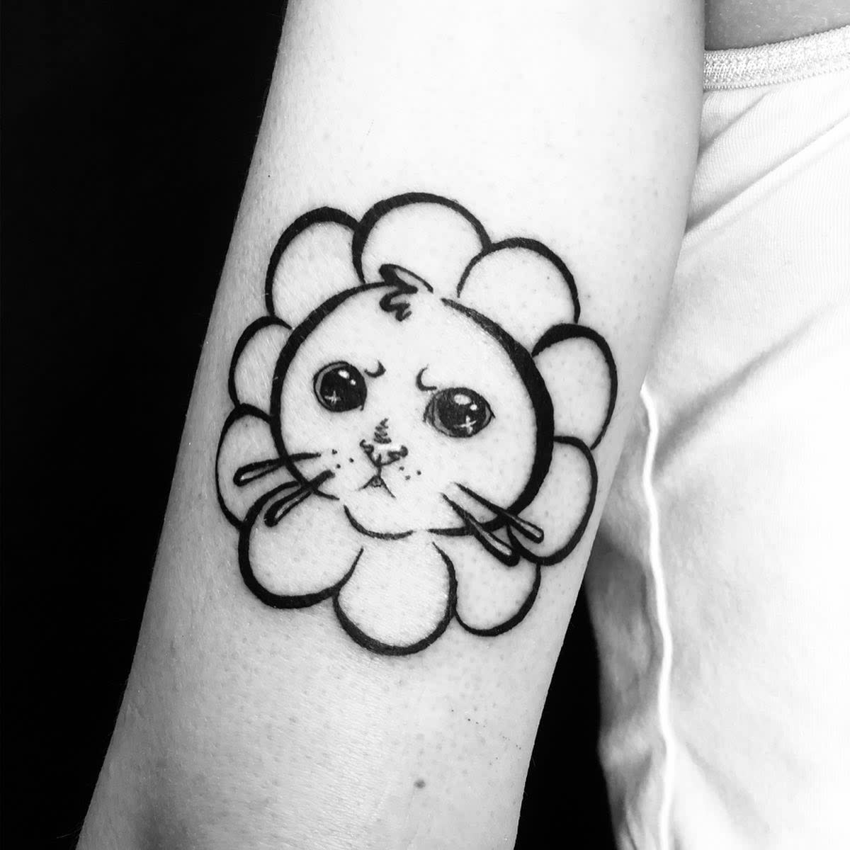 Tattoo of a cute cat's face with whiskers inside a flower-like design