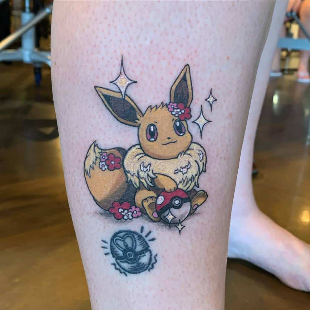 Playful Eevee tattoo with a Pokéball, floral accents, and sparkling details, radiating charm and adventure
