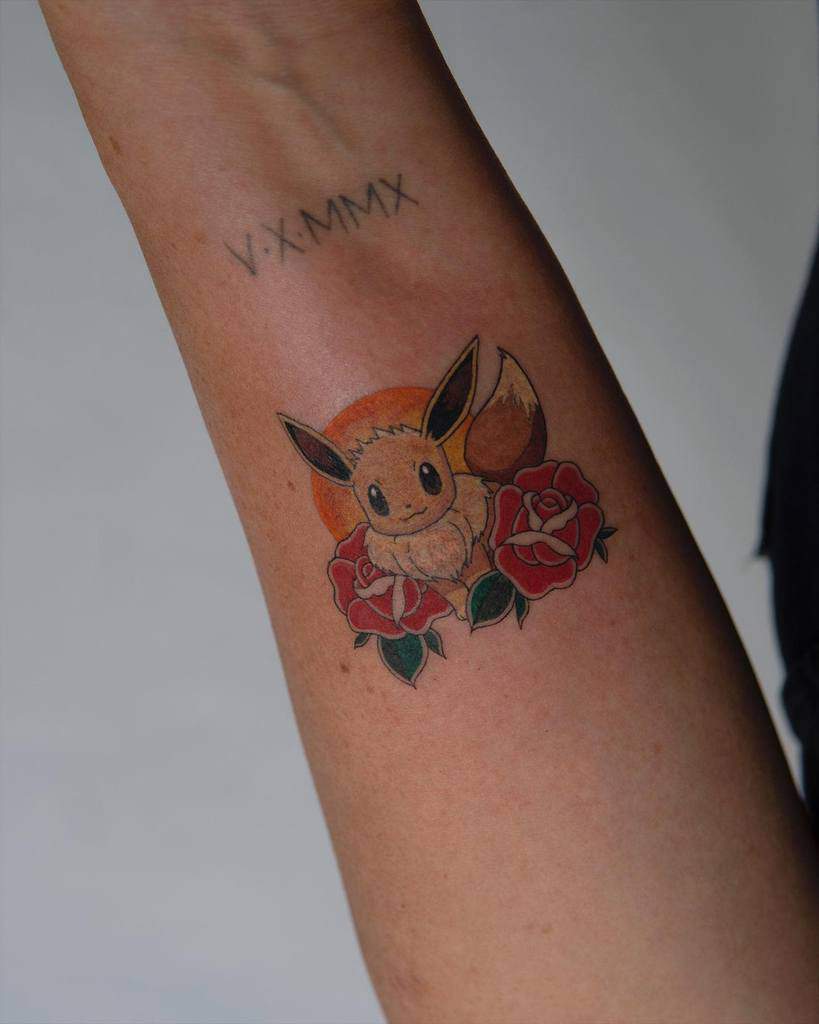 Charming Eevee tattoo surrounded by red roses and a warm orange background, creating a vibrant and elegant design