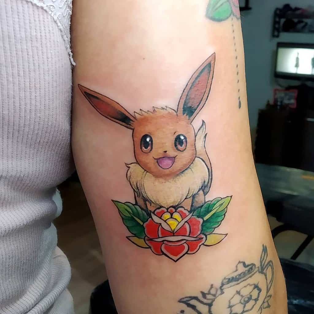 Adorable Eevee tattoo sitting atop a vibrant flower with lush green leaves, exuding a joyful and colorful vibe