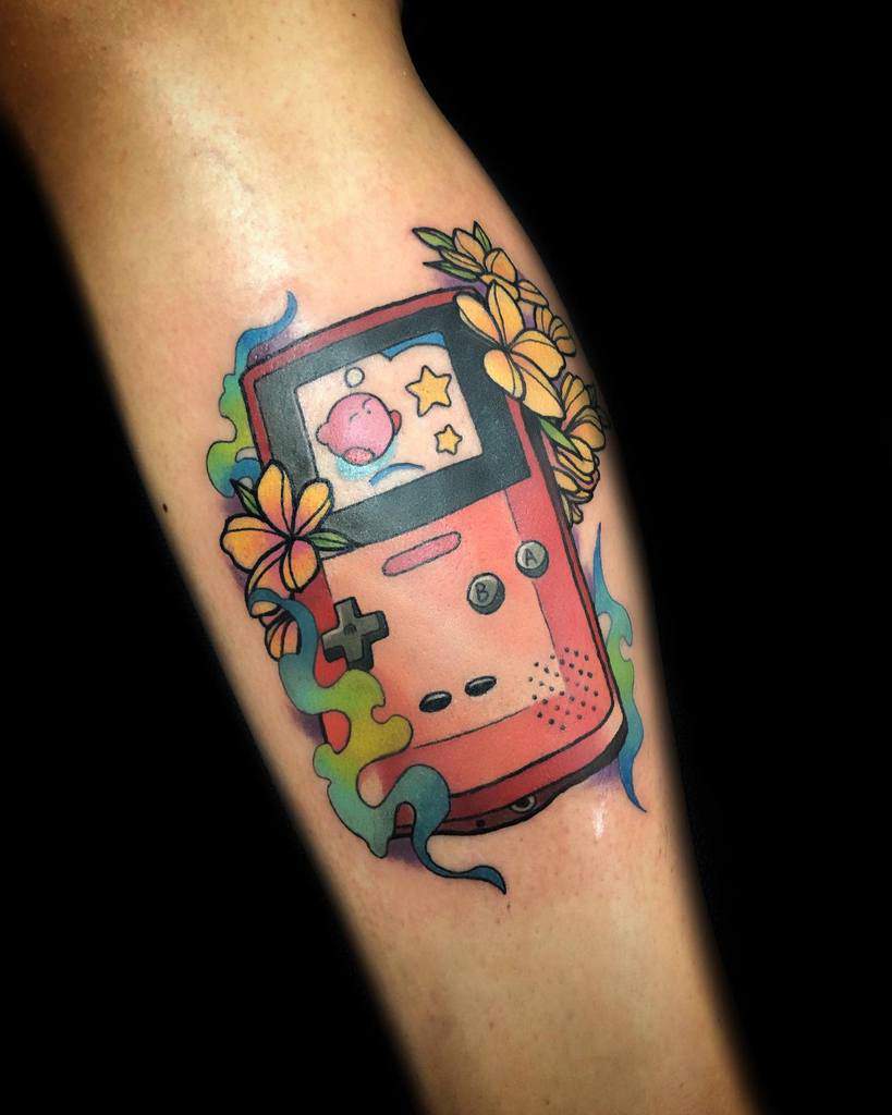 Kirby tattoo inside a retro pink Game Boy screen with 2 stars, surrounded by flowers and colorful smoke