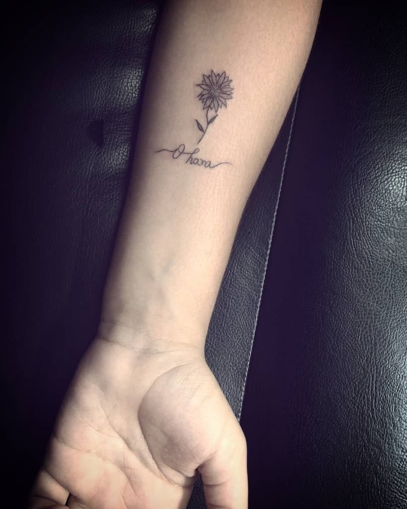 Minimalist 'Ohana' tattoo with a delicate sunflower, symbolizing family, warmth, and positivity.
