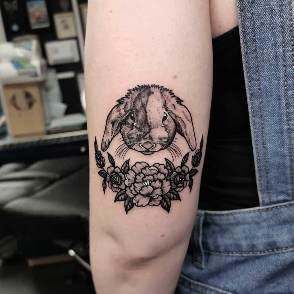 Tattoo of a rabbit's head with long ears above detailed flowers