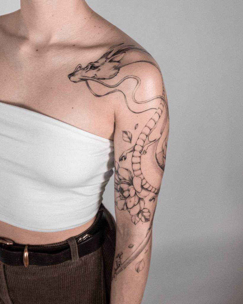 Elegant black and grey tattoo of Haku in dragon form from Spirited Away, with delicate floral details