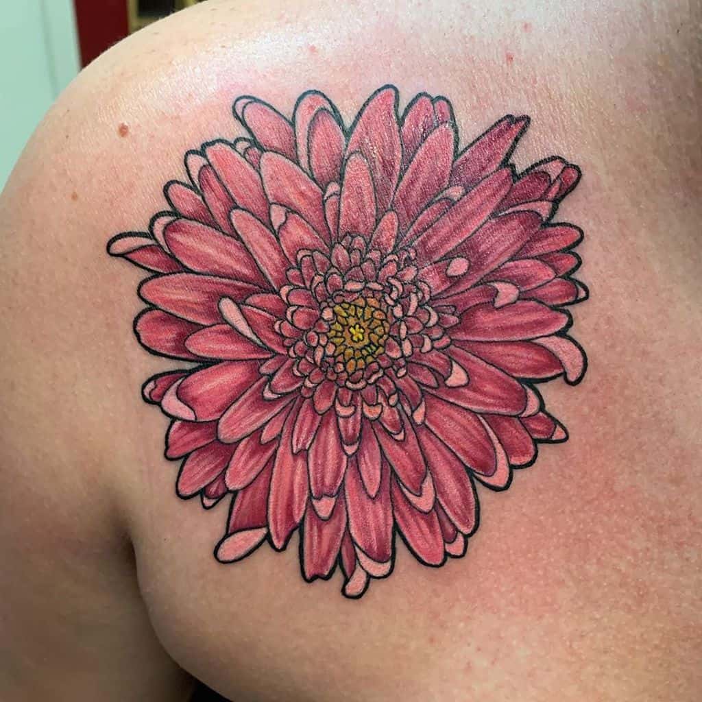 Close-up of a vibrant pink chrysanthemum tattoo, featuring detailed petals and a yellow center
