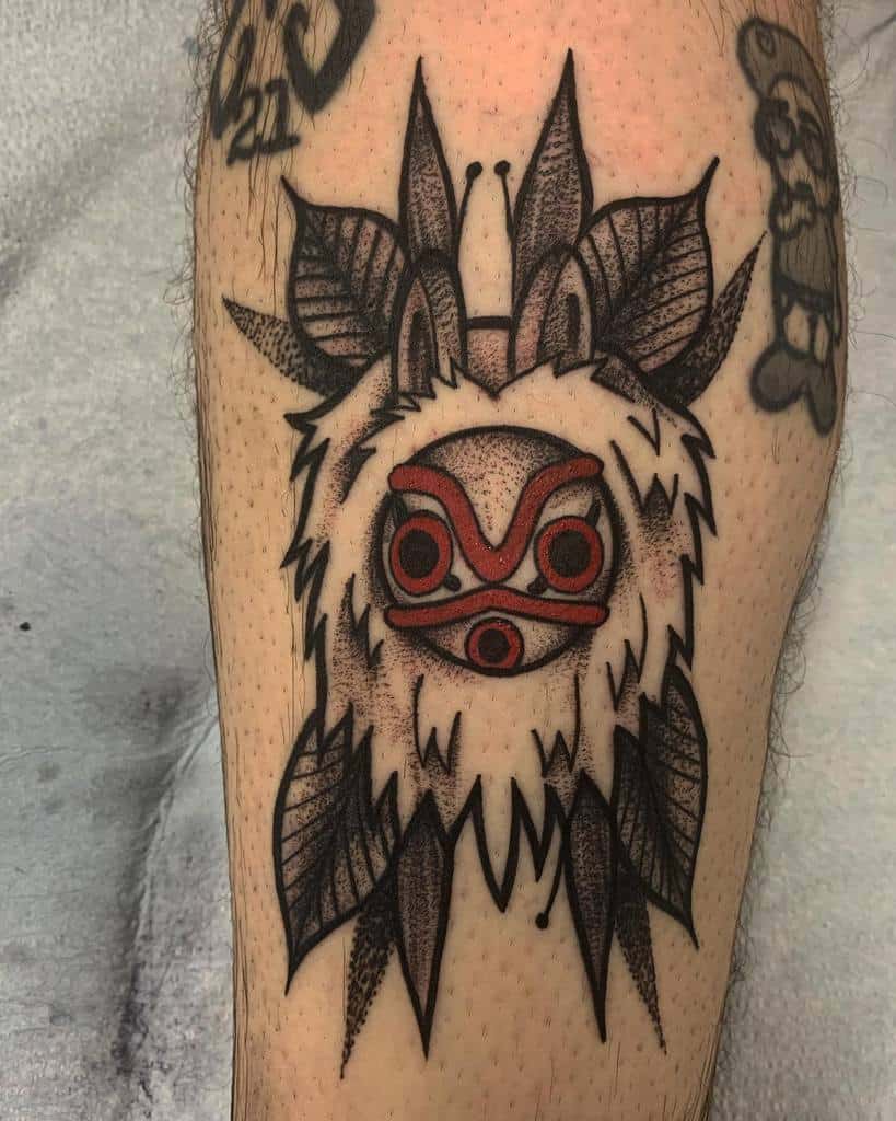 Bold black and red tattoo of Moro’s wolf mask with detailed linework and textured shading, framed by large, stylized wolf ears and leaves.