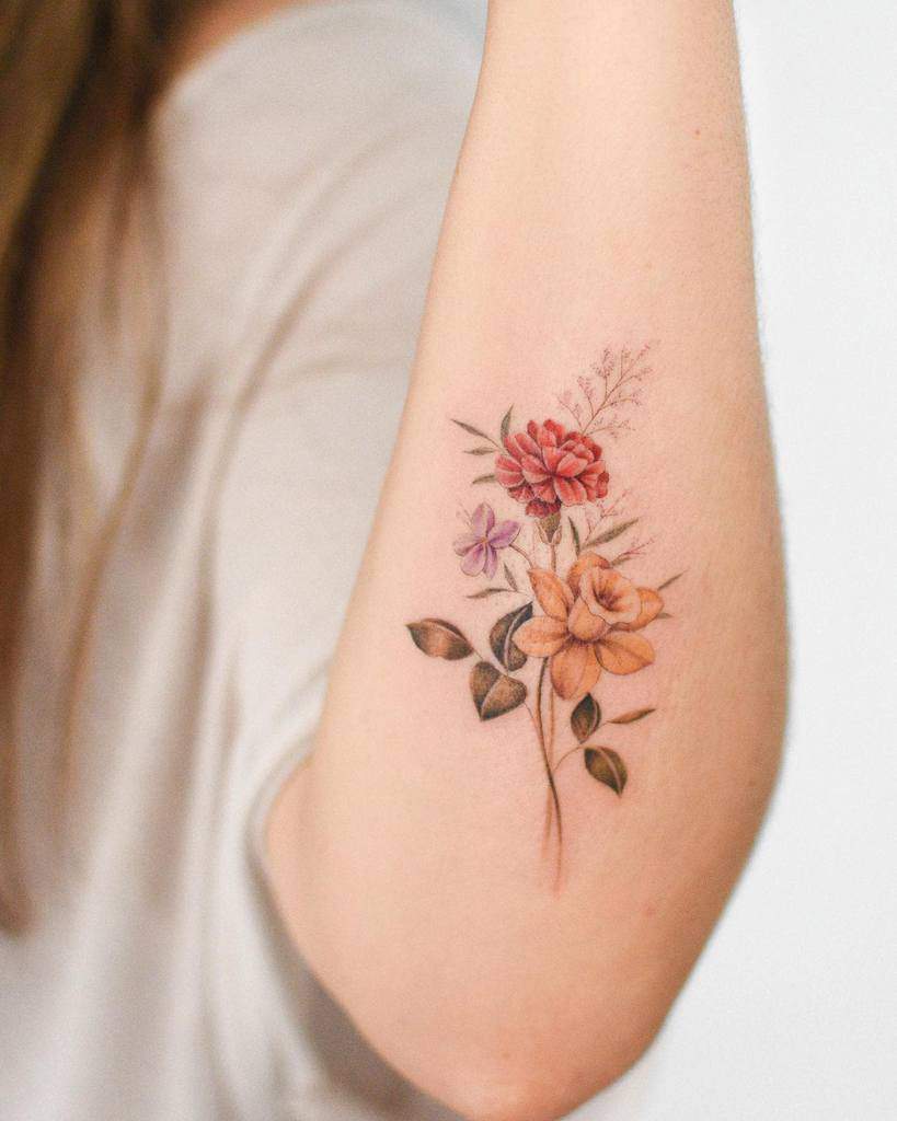 A delicate carnation tattoo featuring red and yellow flowers and green leaves
