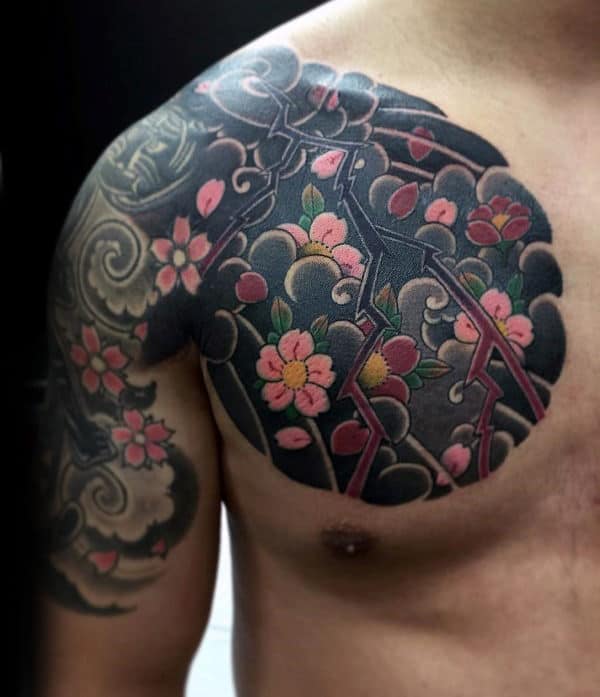Japanese-style chest and arm tattoo featuring bold black clouds, pink cherry blossoms, and intricate lightning bolt details for a dynamic look