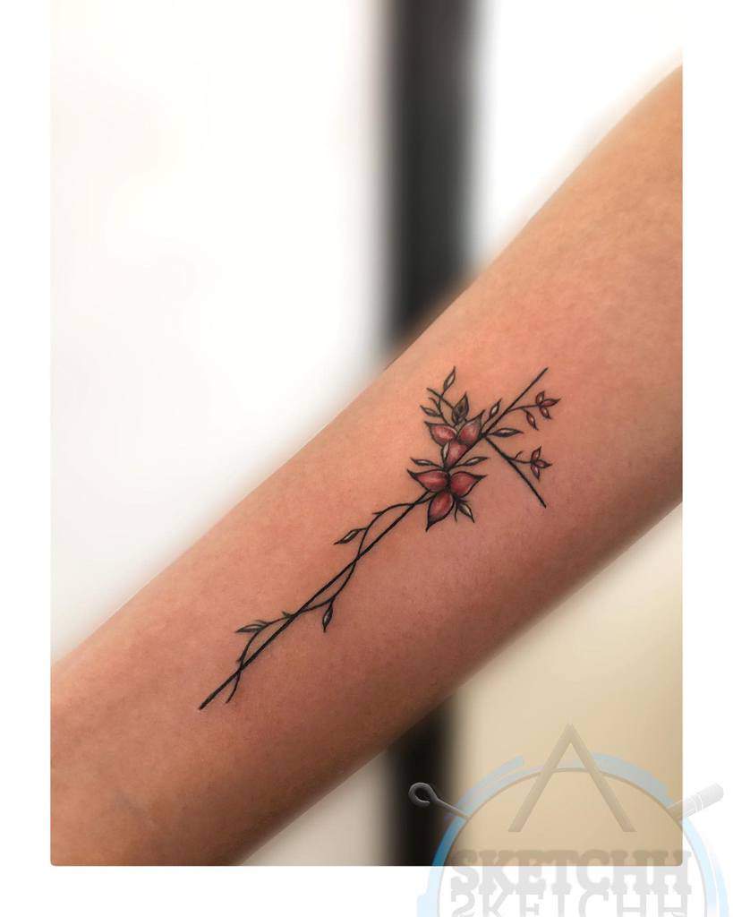 A forearm tattoo of a rose branch intertwined with a subtle cross, featuring vibrant red blooms and lush green leaves
