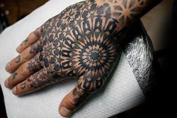 Hand with intricate geometric-patterned tattoos resting on a paper towel