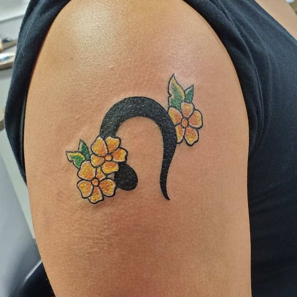 Leo astrological symbol tattoo with colorful flowers, combining bold lines with nature-inspired elements.