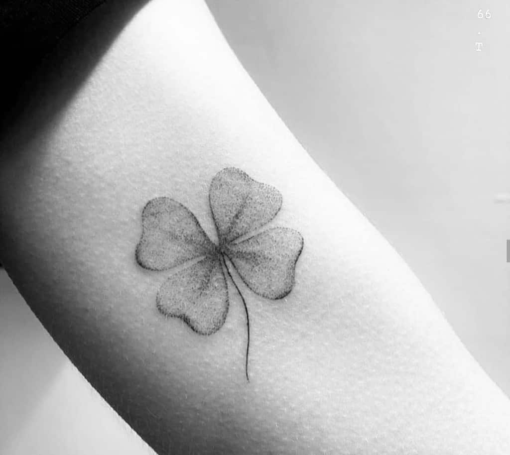 Black and white four-leaf clover tattoo with intricate single needle detail on a person's arm