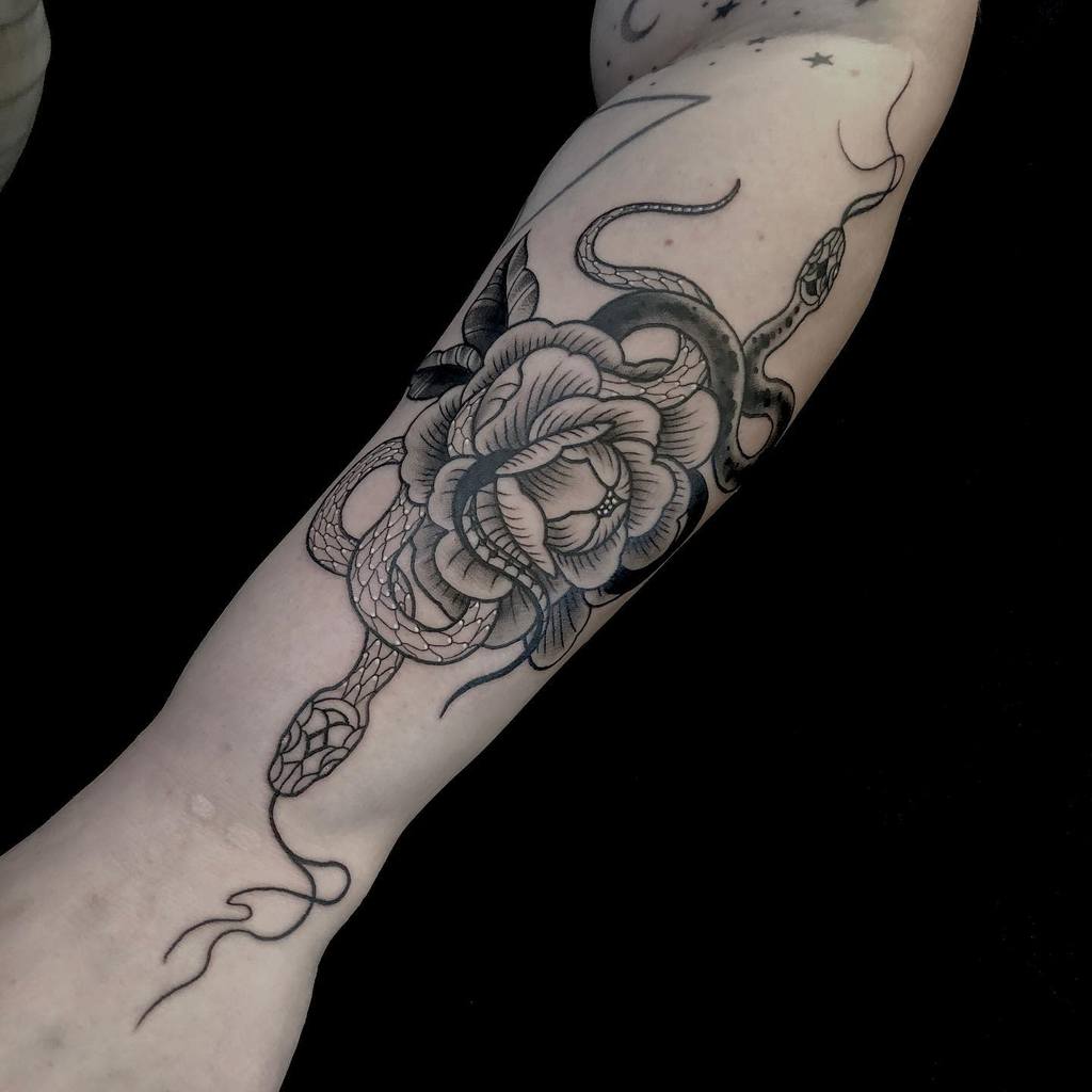 Arm tattoo of a black and grey snake intertwined with a rose