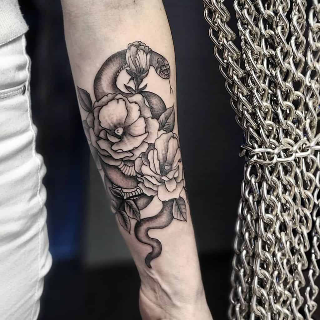 Forearm tattoo of a snake entwined with roses, next to a chain