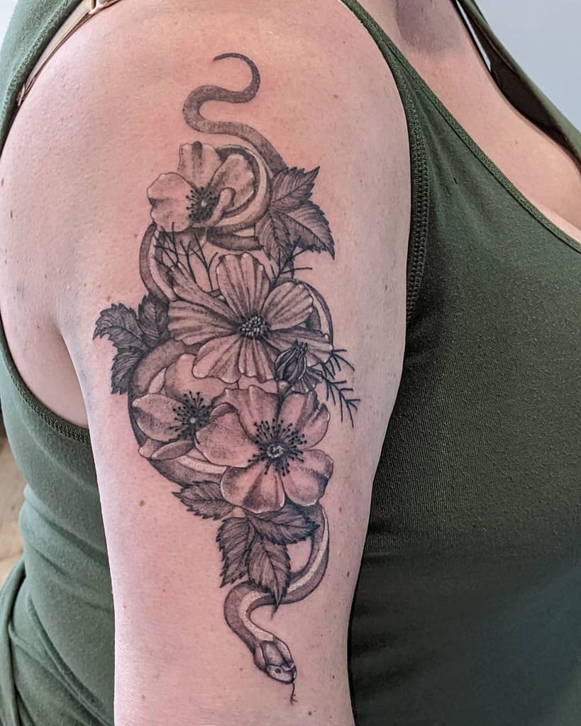 Tattoo of a snake intertwined with flowers and leaves on a person's upper arm