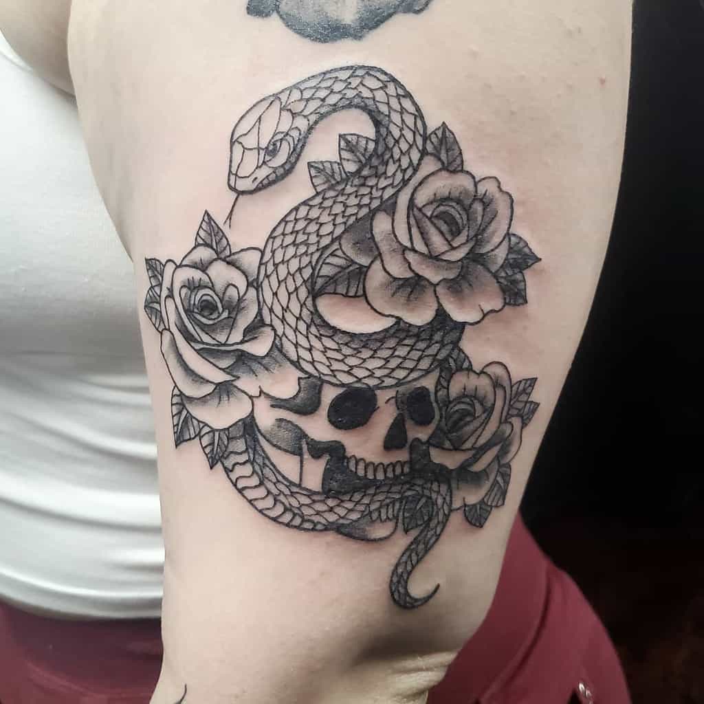 Arm tattoo of a snake coiled around roses and a skull, featuring intricate shading and detail