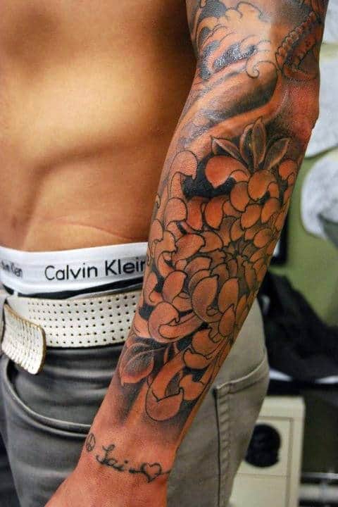 A person's tattooed arm with floral designs in black ink