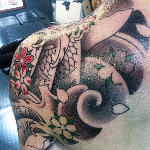 Colorful floral and geometric tattoo covering a shoulder and upper arm