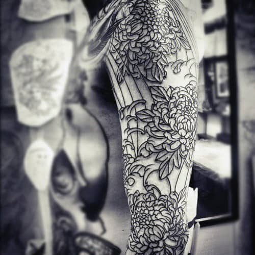 Black and white photo of a detailed flower tattoo sleeve on an arm