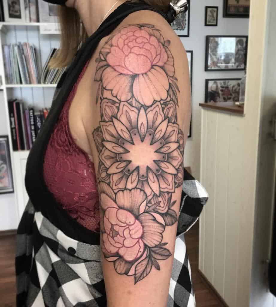 Woman with a floral tattoo sleeve on her left arm, featuring large flowers and leaves