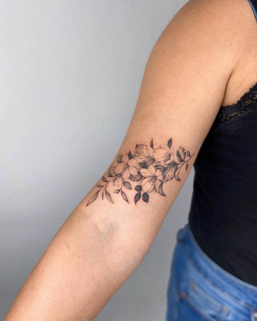 Arm tattoo featuring flowers and leaves in black ink on the inside of the forearm