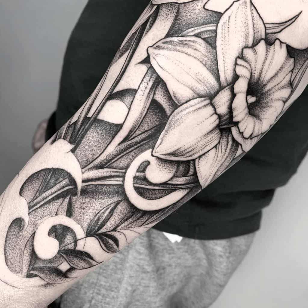 A bold black-and-gray tattoo of daffodils, intricately shaded with swirling, flowing lines that create a dynamic and elegant composition.