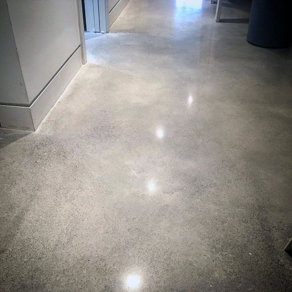 Modern flush baseboard with polished concrete flooring and soft lighting reflections.