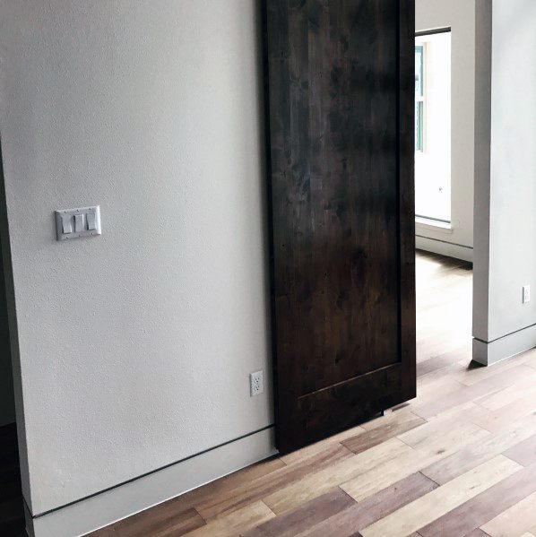 Flush recessed baseboard with light wood flooring and a dark wooden sliding door.