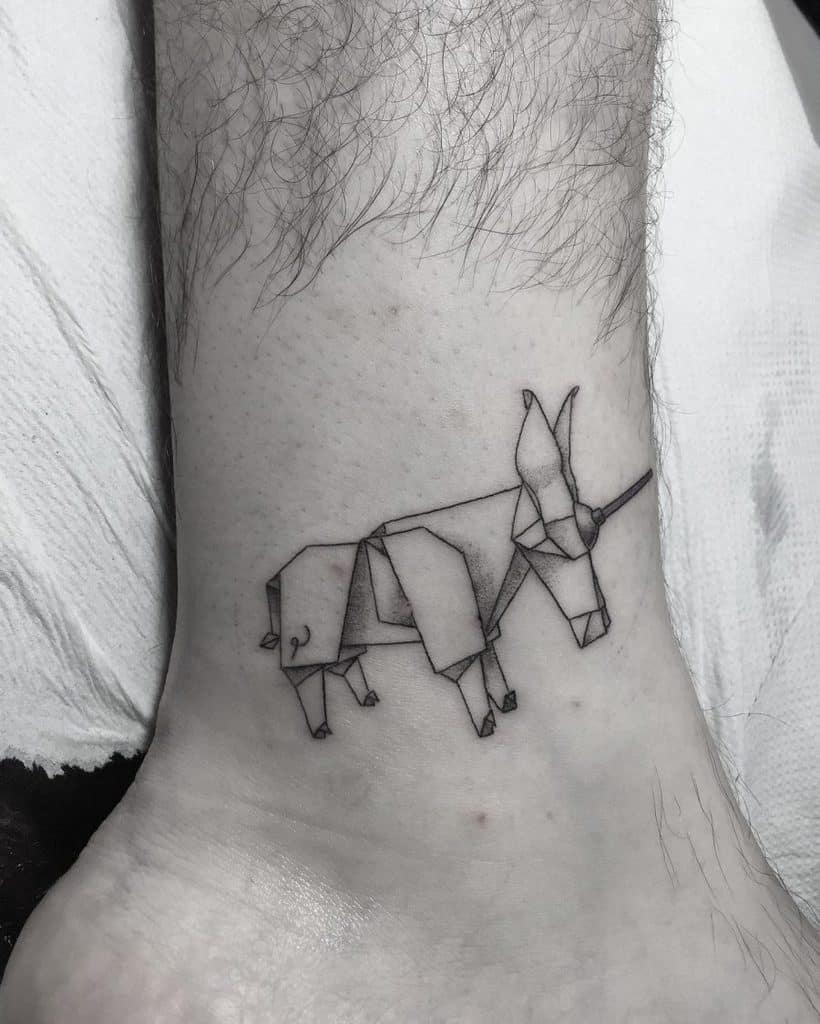 Minimalist black ink tattoo of an origami-style unicorn on the ankle, featuring fine lines and geometric shapes for a modern aesthetic.