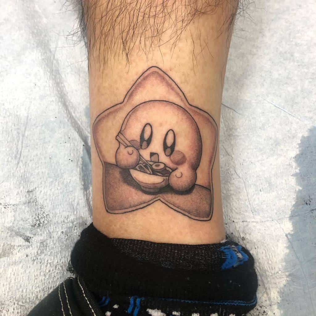 Black and grey Kirby tattoo inside a star, happily eating a bowl of ramen with chopsticks