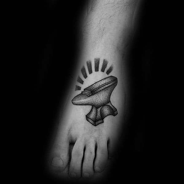 Dotwork anvil tattoo on the top of the foot with bold black rays above, giving it a radiant and impactful appearance.
