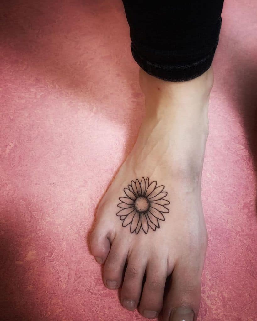 Top of foot traditional black and grey fine line daisy tattoo