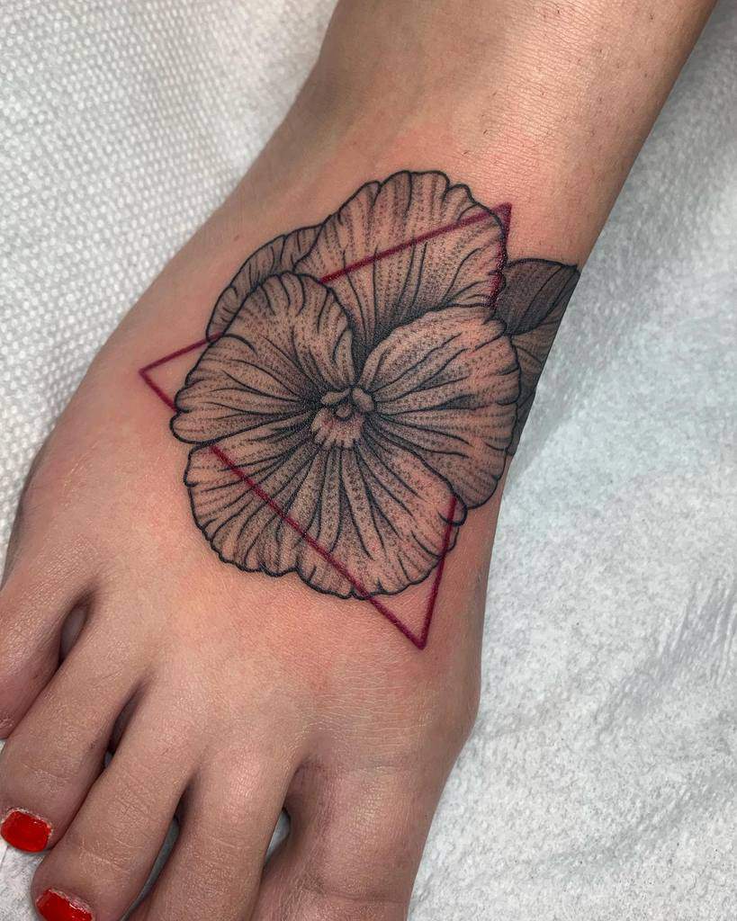 Black and grey violet pansy tattoo with fine dotwork shading, accented by a bold red geometric triangle for a modern touch
