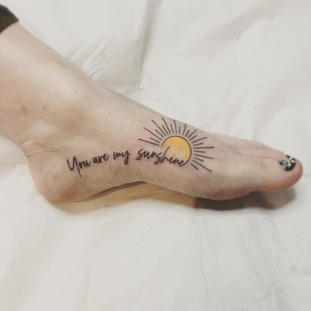 A foot tattoo reads "You are my sunshine" with a sun design