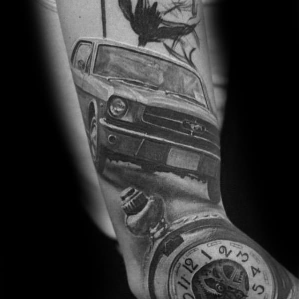 Realistic black and grey Ford Mustang tattoo on forearm, featuring a dynamic front view, pocket watch, and crow for a dramatic effect.