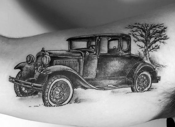 Black and grey vintage Ford Model A tattoo on arm, featuring fine details, realistic shading, and a lone tree for a classic nostalgic look.