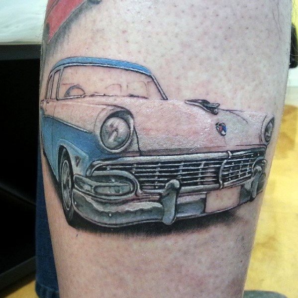 Realistic Ford classic car tattoo on leg, featuring a detailed blue and white vintage design with soft shading and a nostalgic front view.