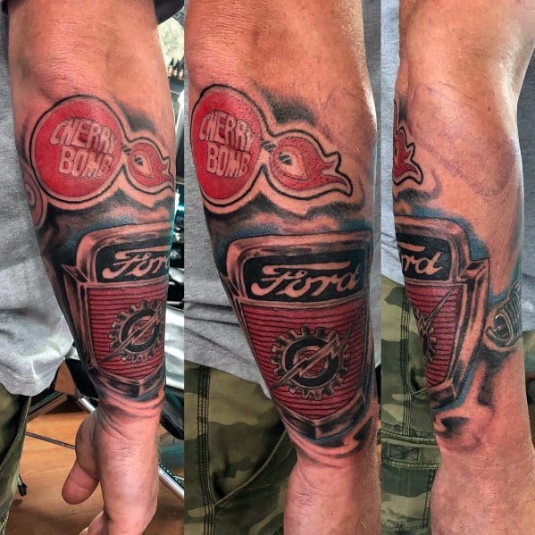 Bold Ford-themed tattoo sleeve on forearm, featuring a detailed vintage Ford grille, Cherry Bomb mufflers, and a dynamic 3D effect.