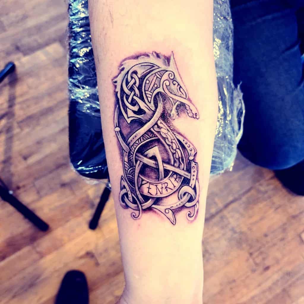 Forearm tattoo of Fenrir in detailed Nordic knotwork, featuring the Valknut symbol and runic-inspired designs