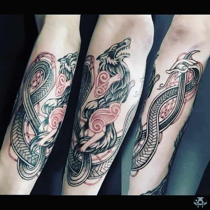Forearm tattoo featuring Fenrir entwined with a serpent in Nordic knotwork, highlighted by red swirls and intricate details